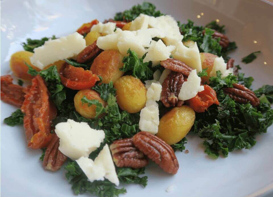 Maaltijdsalade van roergebakken boerenkool, gedroogde tomaat, pecannoten en pecorino